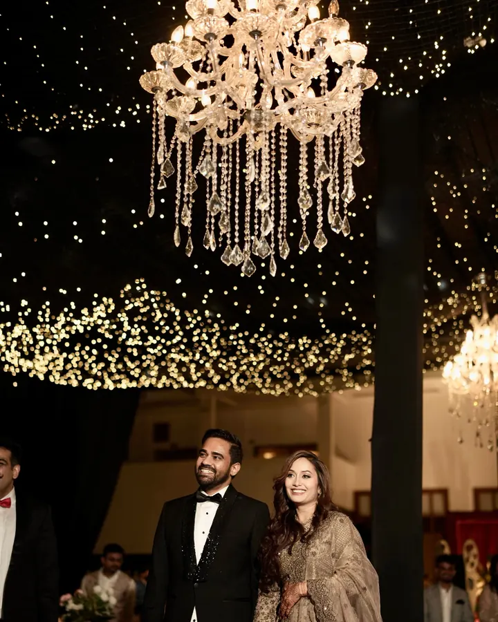 A couple at a sangeet night under a crystal chandelier